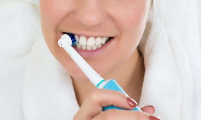 Mulher com uma escova de dentes elétrica