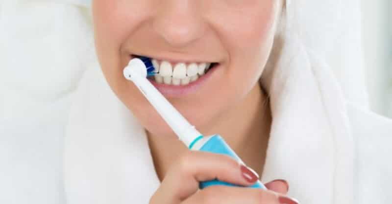 Mulher com uma escova de dentes elétrica
