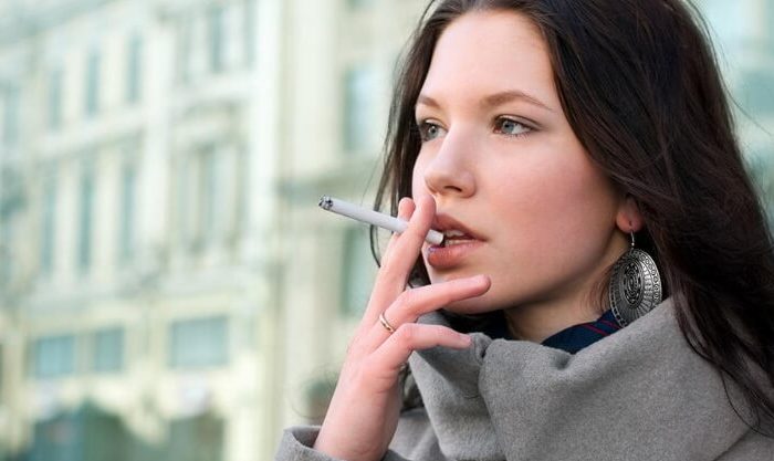 Jovem mulher a fumar um cigarro