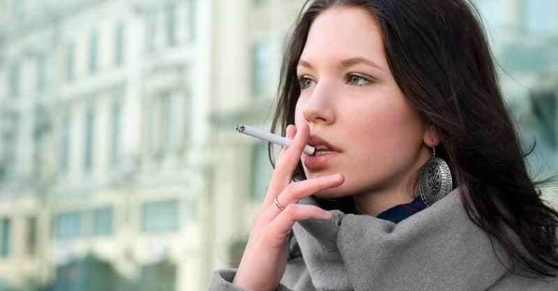 Jovem mulher a fumar um cigarro