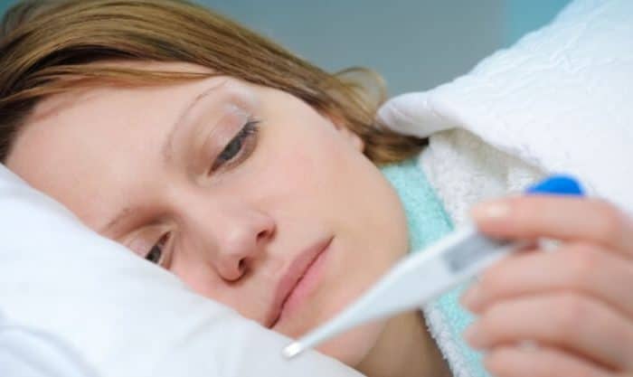 Mulher a medir a temperatura por causa da febre alta