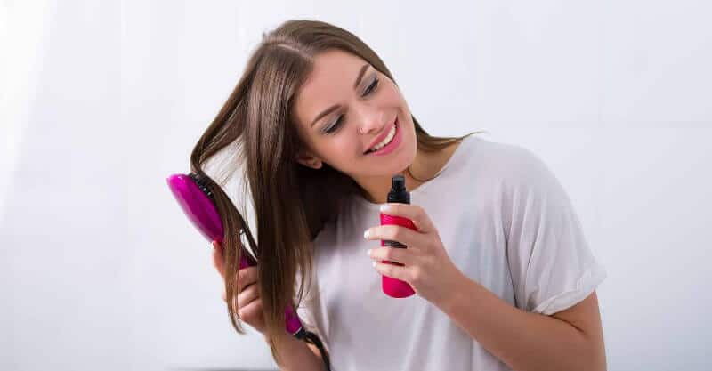 Mulher a aplicar shampô seco no cabelo