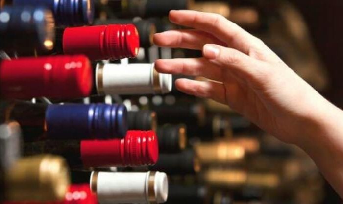 Mulher escolhe vinhos da sua adega caseira