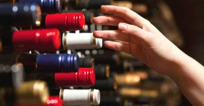 Mulher escolhe vinhos da sua adega caseira