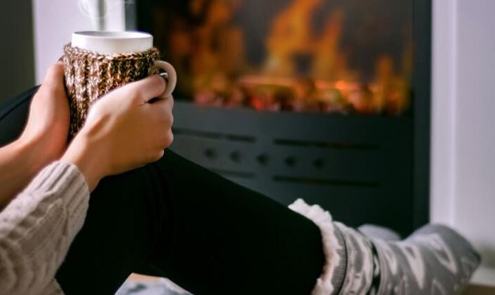 Mulher desfruta do calor de uma lareira com acendalhas ecológicas