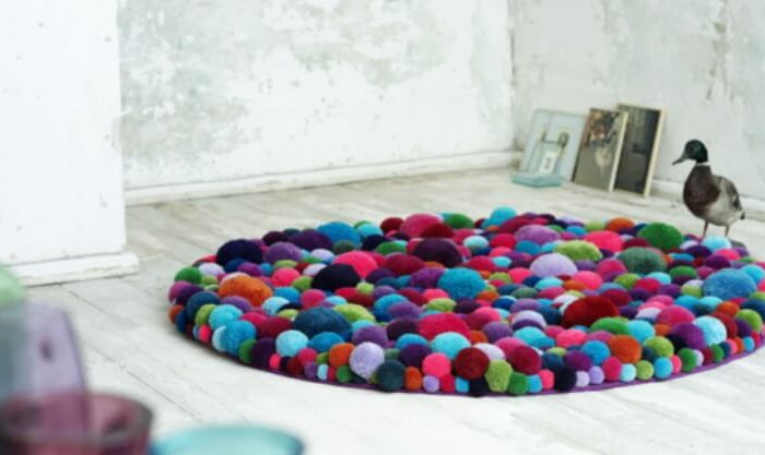 Pompons de lã em formato tapete a decorar uma divisão da casa