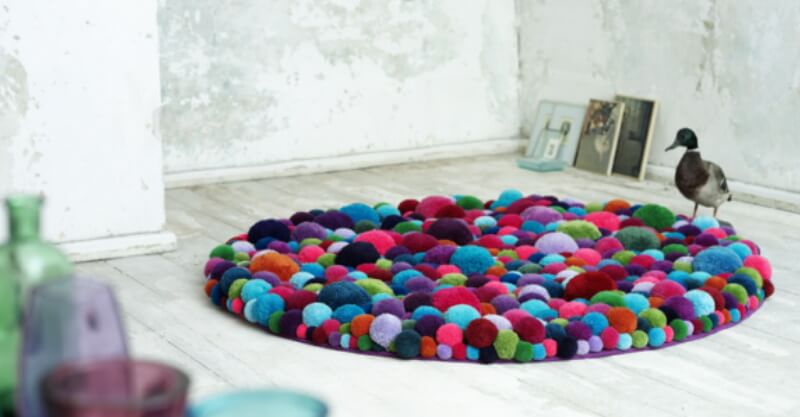 Pompons de lã em formato tapete a decorar uma divisão da casa
