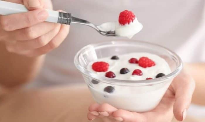 Mulher com uma taça de iogurte e frutos ricos em probióticos
