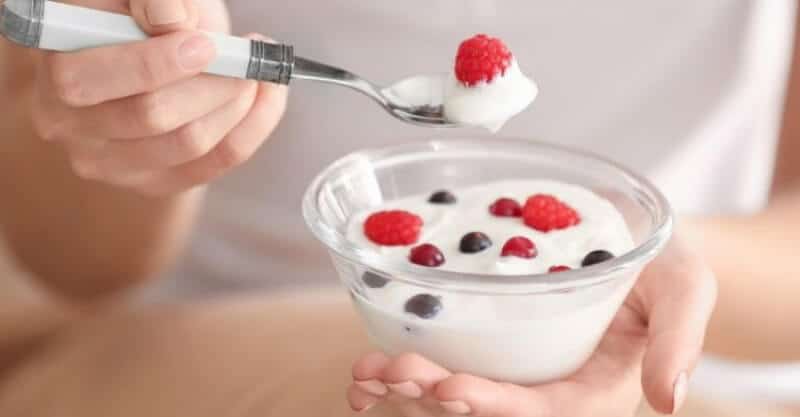 Mulher com uma taça de iogurte e frutos ricos em probióticos