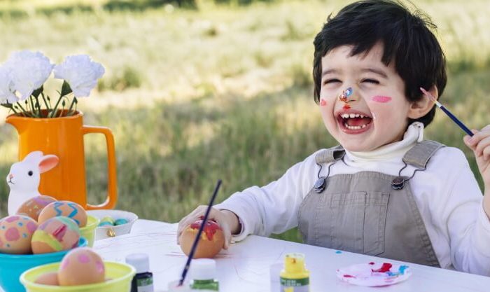 Menino feliz a pintar ovos da Páscoa