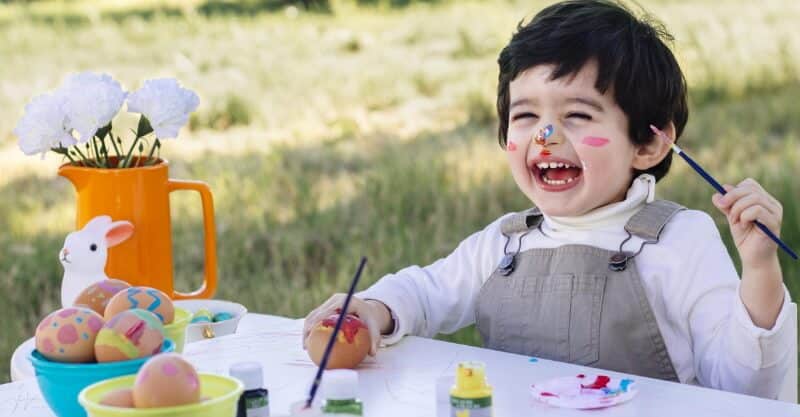 Menino feliz a pintar ovos da Páscoa
