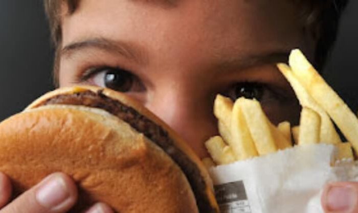 Criança com comida que promove a obesidade