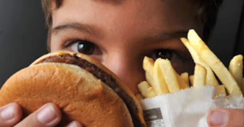 Criança com comida que promove a obesidade